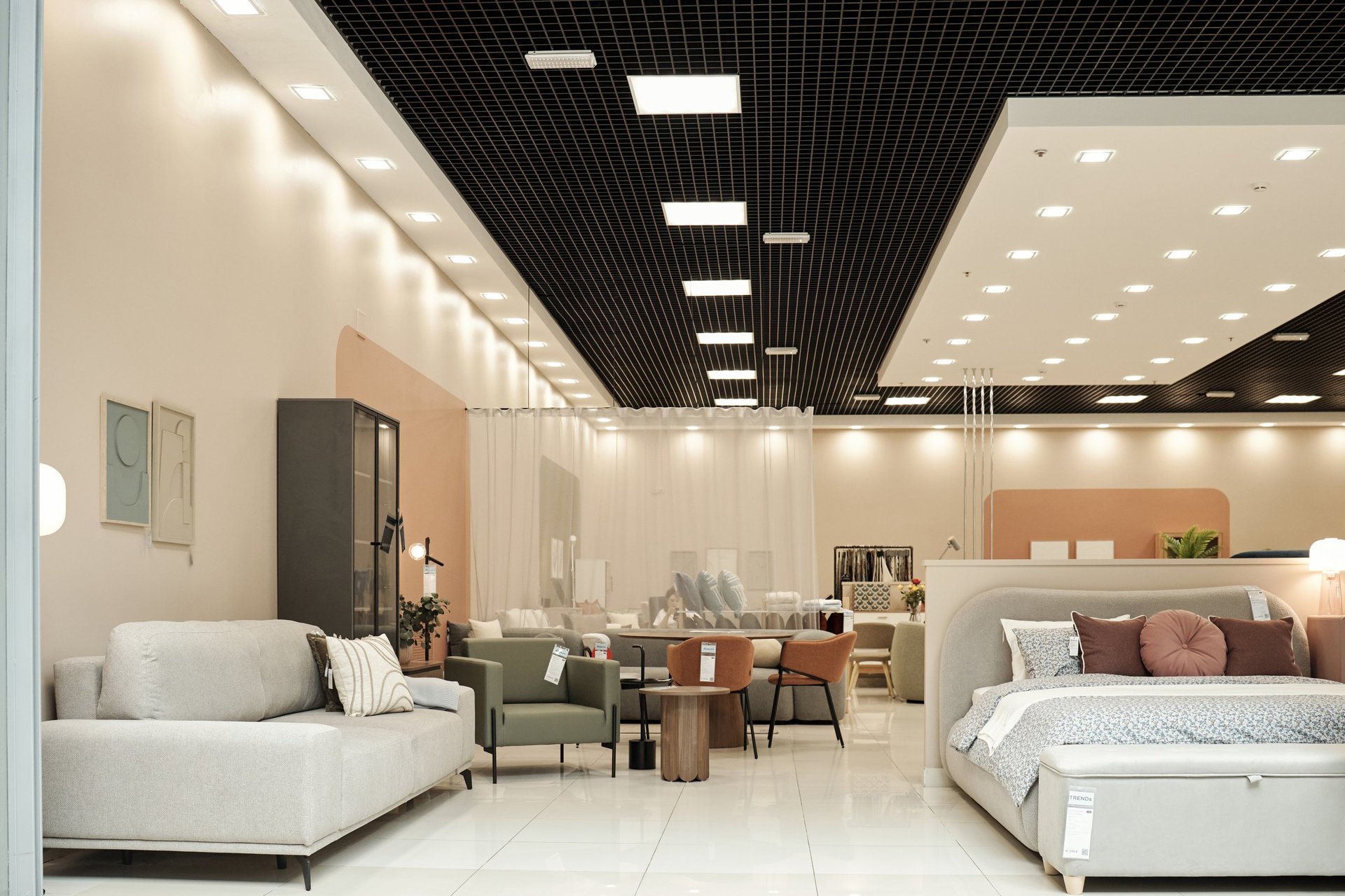Modern furniture store interior displaying contemporary sofas, armchairs, tables, and bed arranged in spacious showroom