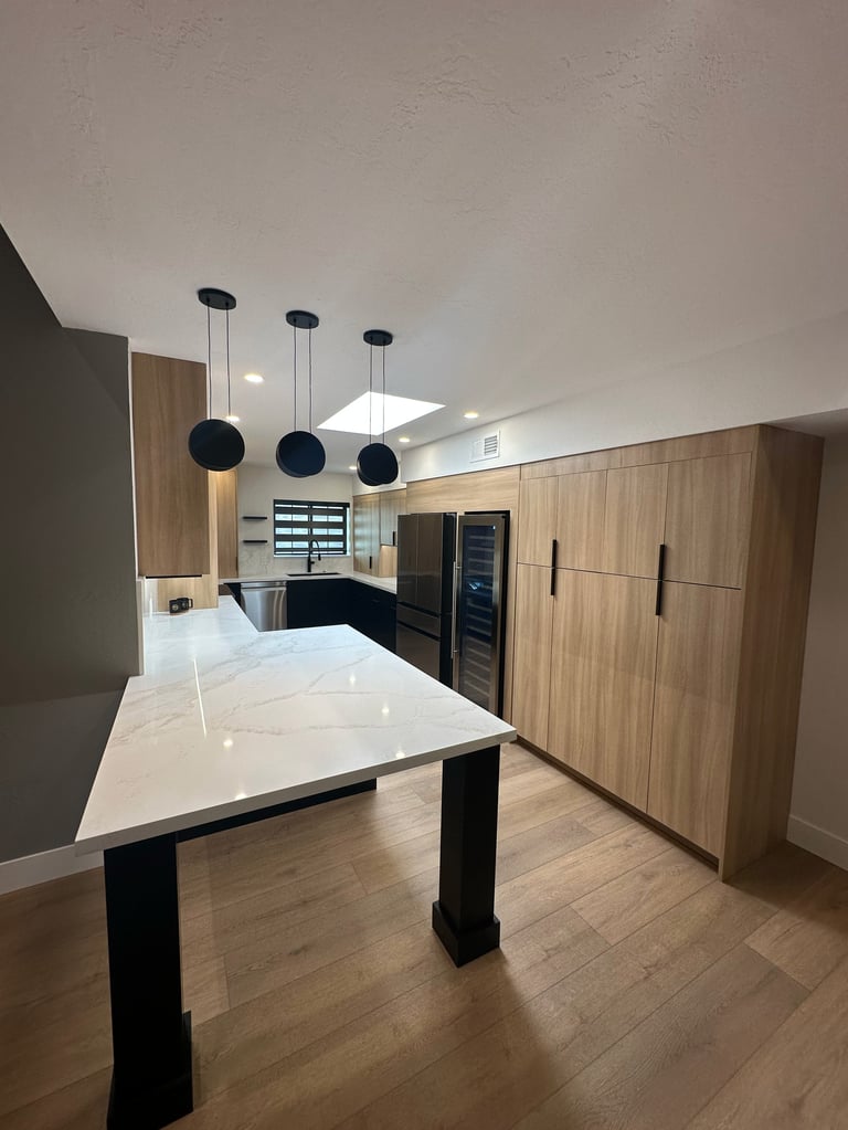 Modern kitchen with white quartz island, wood cabinets, pendant lights, and stainless steel appliances