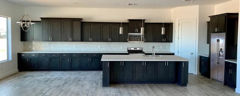 Modern kitchen with dark cabinetry, white tile backsplash, large island, and stainless steel appliances