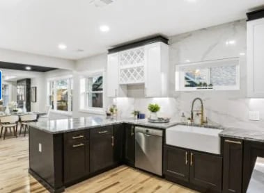 Modern kitchen with dark cabinetry, white countertops, stainless steel appliances, and a large island with seating area